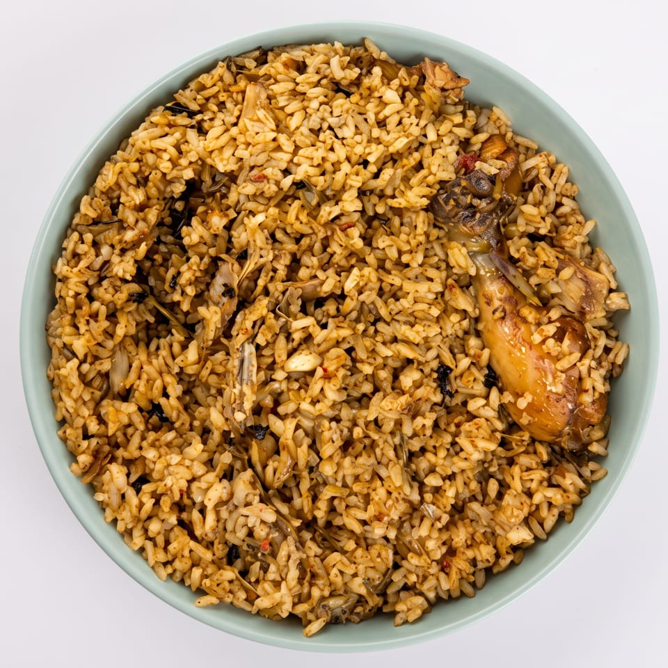 Overhead view of a light blue bowl filled with chicken and rice, on a white background.